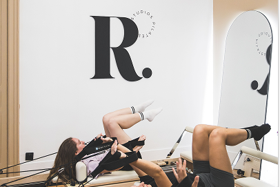 Femme pratiquant le Pilates au sol sur tapis dans un studio moderne avec logo Rebela, comparaison avec machine Reformer