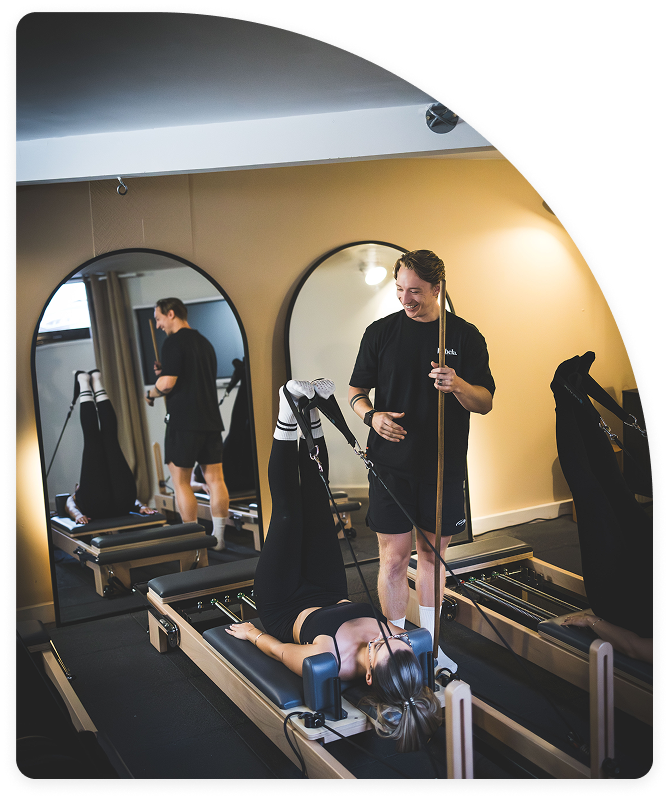 Etirement et tonification du corp durant une séance de Pilates reformer dans notre studio de Balma