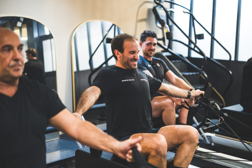 hommes pratiquants du pilates reformer a 4